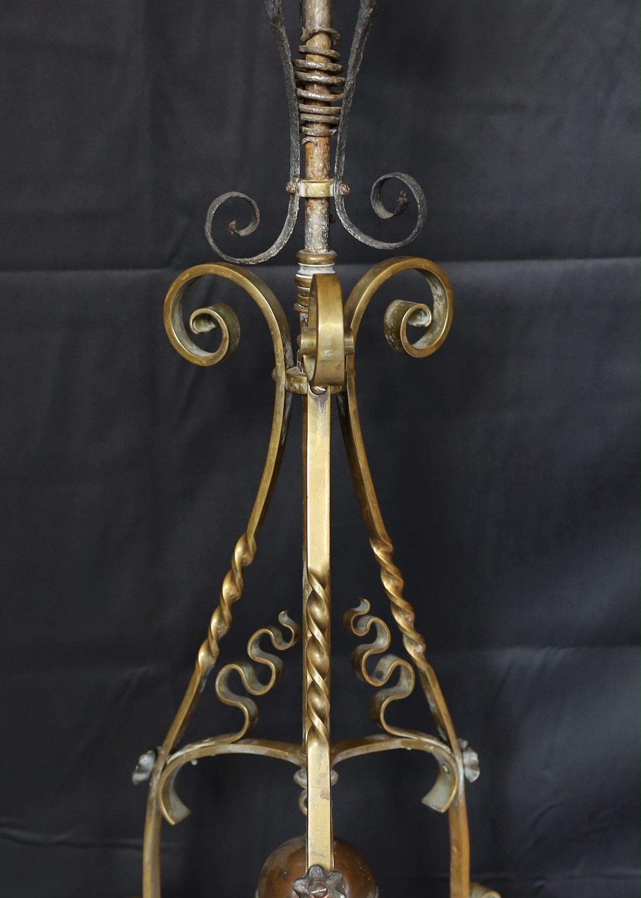 A late Victorian Arts and Crafts wrought iron and brass miniature oil lamp standard, in the manner of Benson, with duplex mechanism and later cranberry tinted glass shade, height without shade 96cm.